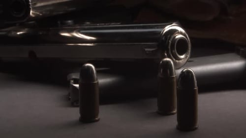 Handgun and Bullets on Dark Surface