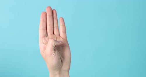 Man counting with fingers on light blue background, closeup