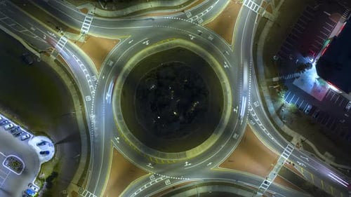 Top View of City Street Traffic on Roundabout Intersection at Night with Fast Moving Cars