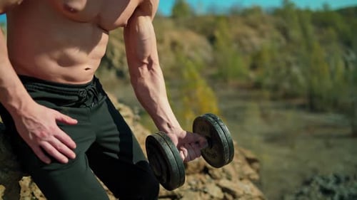 Muscular Man Lifting Dumbbell Outdoors