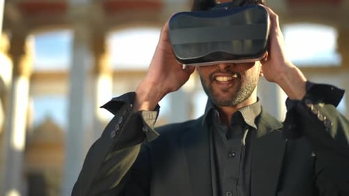 Smiling Middle Eastern Man in VR Headset Standing on Sunny Urban City Street