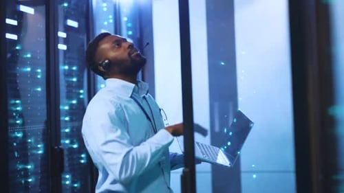 A Focused Man Works in a Server Room Dedicated to Monitoring Systems