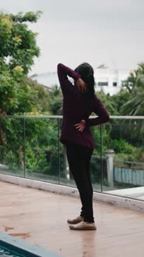 Femme asiatique étirant ses bras à l'extérieur près de la piscine