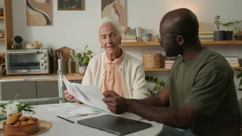 Elderly Woman Doing Tax Payments with Black Man Helping