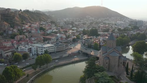 Aerial view of Metekhi church in downtown Tbilisi, Georgia at sunset, sunrise with mountains in the