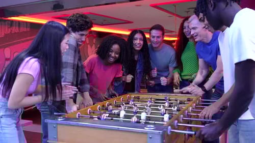 Friends Playing Foosball and Having Fun at Bowling Alley
