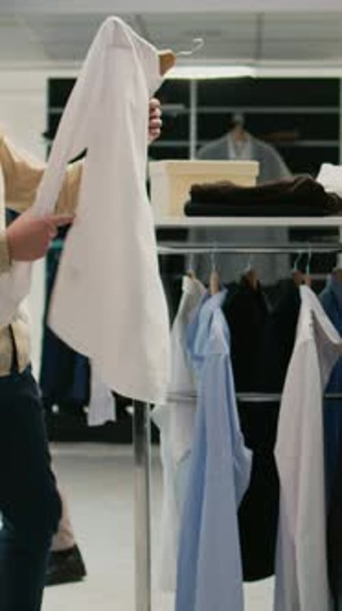 Vídeo vertical: cliente masculino analisando coleção de moda em uma boutique