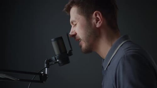 Man Speaking Into Studio Microphone Against Dark Background