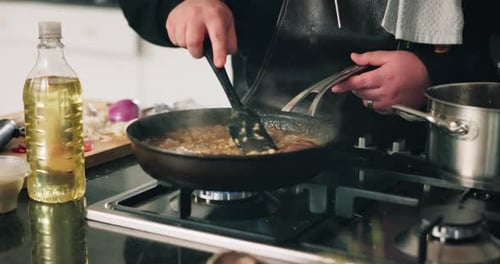 Person Cooking Food on Stovetop in Kitchen
