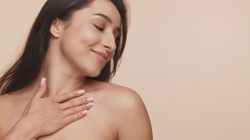 Smiling Young Woman Touching Shoulder in Beauty Shot