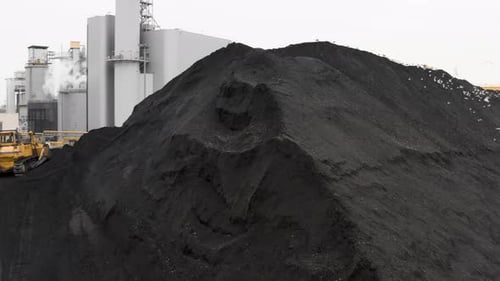 Ein Planierraupenbagger harkt den Kohlevorrat für die Heizperiode zu einem großen Haufen zusammen.