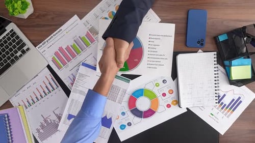Business People Shake Hands Over Data at Desk