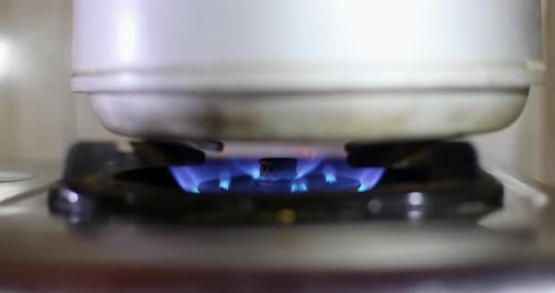 Gas Stove Igniting Flames Under Pot in Kitchen