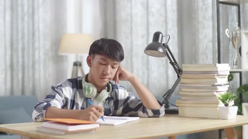 Bored Asian Teenager Studying At Home, Asia Teen Writing While Sitting On The Table
