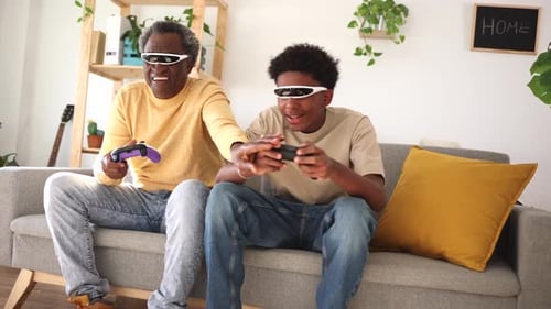 Grandfather and Teen Playing Video Game on Couch