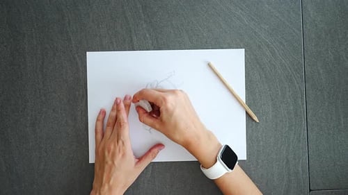 Close Up of Woman Hands Erasing Pencil Doodles with Eraser on Paper in Home Office Editing Process