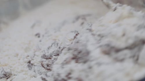 Mixing flour and chocolate brownie cake mix with a spoon in a bowl. Slow motion.