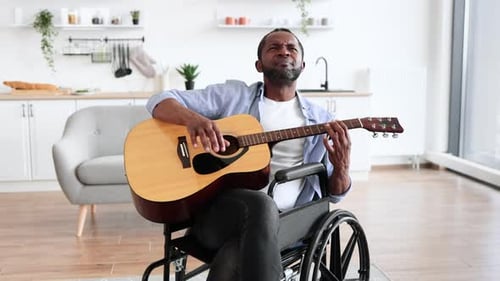 Man Plays Guitar in Wheelchair at Home