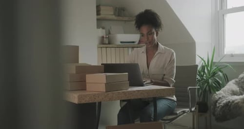 Woman Working on Laptop with Shipping Boxes