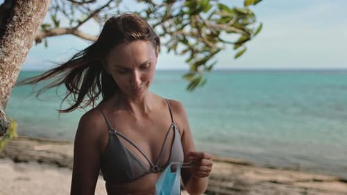 Young Woman Putting on Protective Face Mask at the Beach