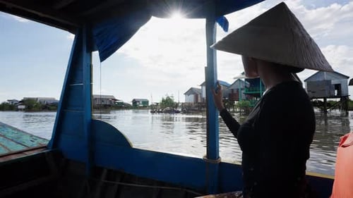 Woman in Hat Rides Boat Through Floating Village