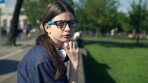 Worried young woman sits pensive on ledge in city park reflecting on her troubles