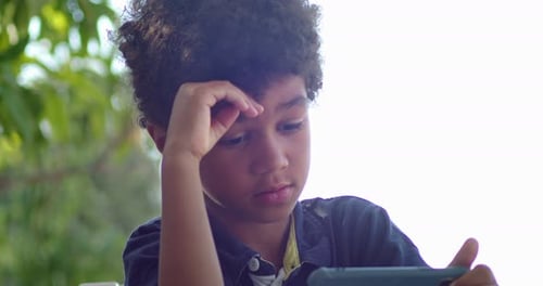 Child Looking at Cellphone Outside on Sunny Day
