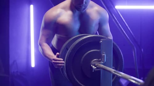 Muscular Man Loading Weights on Barbell in Gym