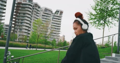 Woman Listens to Music and Dances in Park