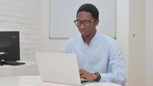 Young Adult Man Works on Laptop in Office