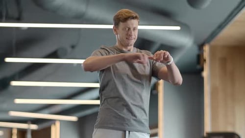 Serious Fitness Man Warming Up Shoulders in Sport Club. Attractive Bodybuilder Preparing