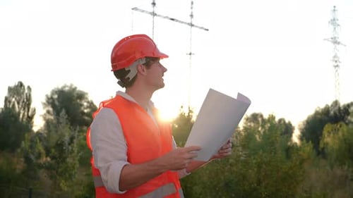 Smiling Electrical Engineer in Helmet Working on Repair of Electrical High Voltage Pylons Outdoors