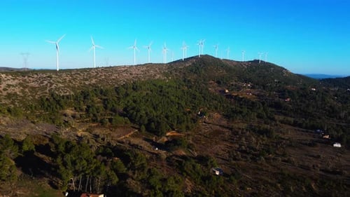 Aerial drone footage of a wind turbines on mountain ridges generating renewable energy.
