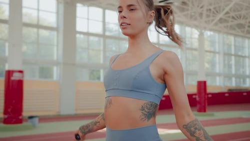 Athletic Woman Warms Up Using Jumping Rope in Sports Complex