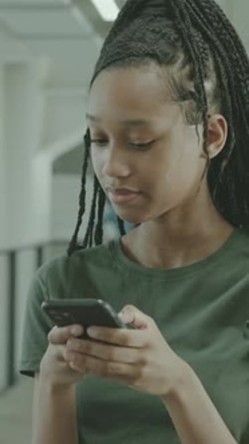 Female High School Student Looking at Smart phone at Break in University