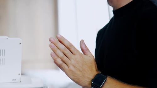 Mains masculines en position de prière. Homme méconnu en t-shirt noir se frottant les mains avec nervosité
.