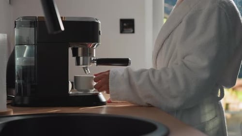 Woman in Robe Brews Coffee in Kitchen