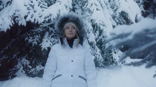 RED Camera of Young Cheerful Woman in Outerwear Walking in Snowy Winter Forest
