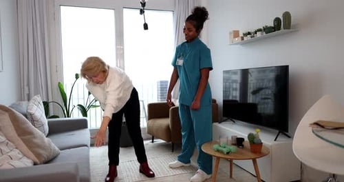 Senior Woman Exercising with Young Adult in Living Room