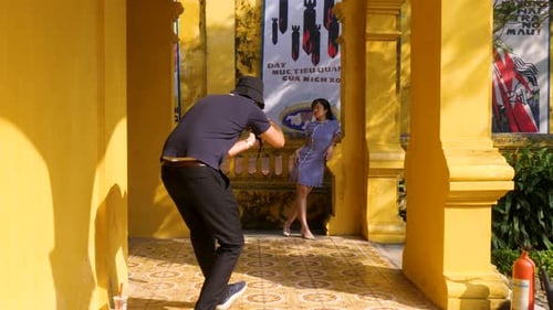 Photographer Taking Pictures of Model by Yellow Building