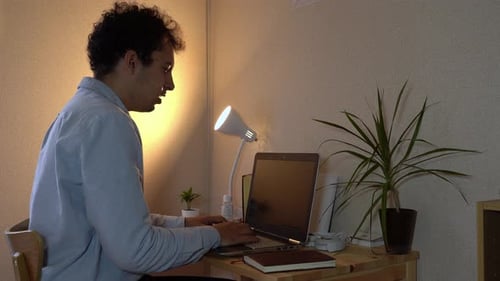 A Man Working On His Laptop At Home Office Sneezes In His Arm To Prevent Spreading Of Coronavirus -