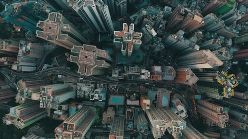 Cinematic drone shot of a city with a lot of skyscrapers during the day. There is many roads with tr
