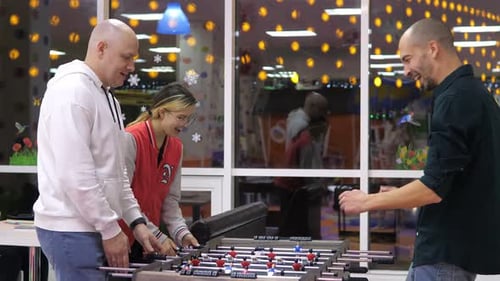 Group of Happy and Joyful Friends Together Playing Table Football in the Playing Center