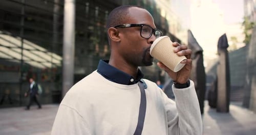 4k video footage of a young businessman drinking coffee while walking in the city