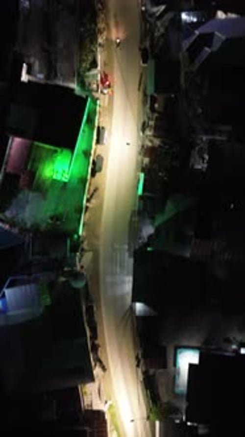 Vertical drone footage of the vehicles driving on illuminated highway roads in the city at night