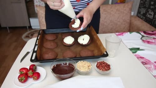 Person Decorating Freshly Baked Cookies with Cream