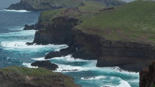 Dramatic Ocean Waves Crashing Against Rugged Green Coastline