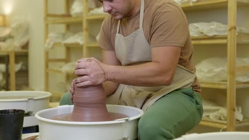 Potter shaping clay spinning on pottery wheel in studio small business workshop