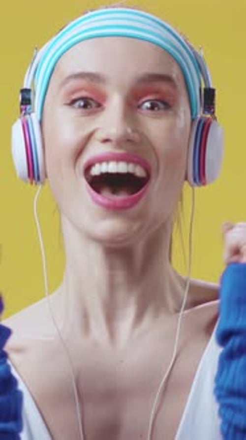 A Stylish Woman Wearing Headphones and a Trendy Headband Against a Bright Yellow Background