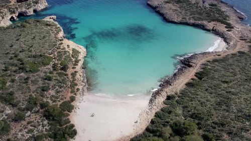 Aerial view of turquoise water beach, rock formations, Cala Varques, Spain.